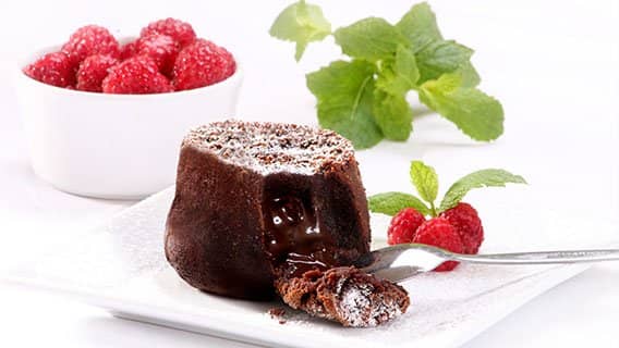 A chocolate pudding with a molten centre, served with raspberries and mint