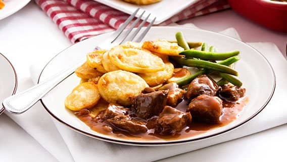 Braised beef in gravy with sliced sauté potatoes and green beans
